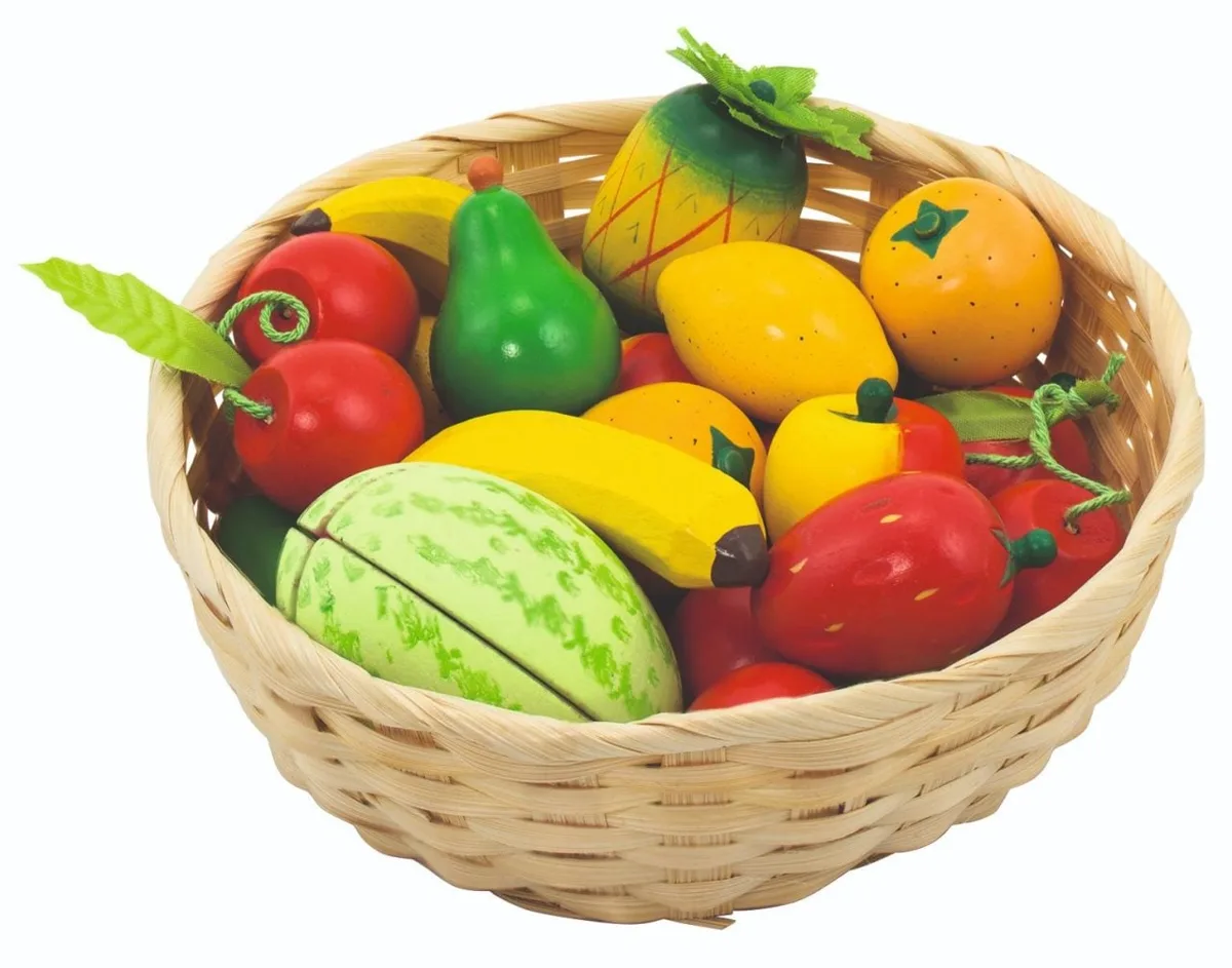 The Goki Fruit in a Basket, a wicker shopping basket filled with a colourful assortment of wooden play fruit including bananas, a pineapple, and strawberries.
