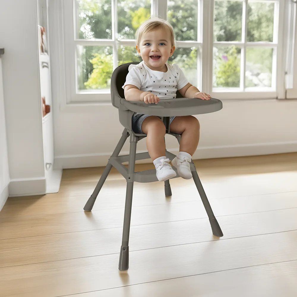 Smiling baby seated in Dolu stone grey high chair with tray, pictured in a bright modern kitchen setting