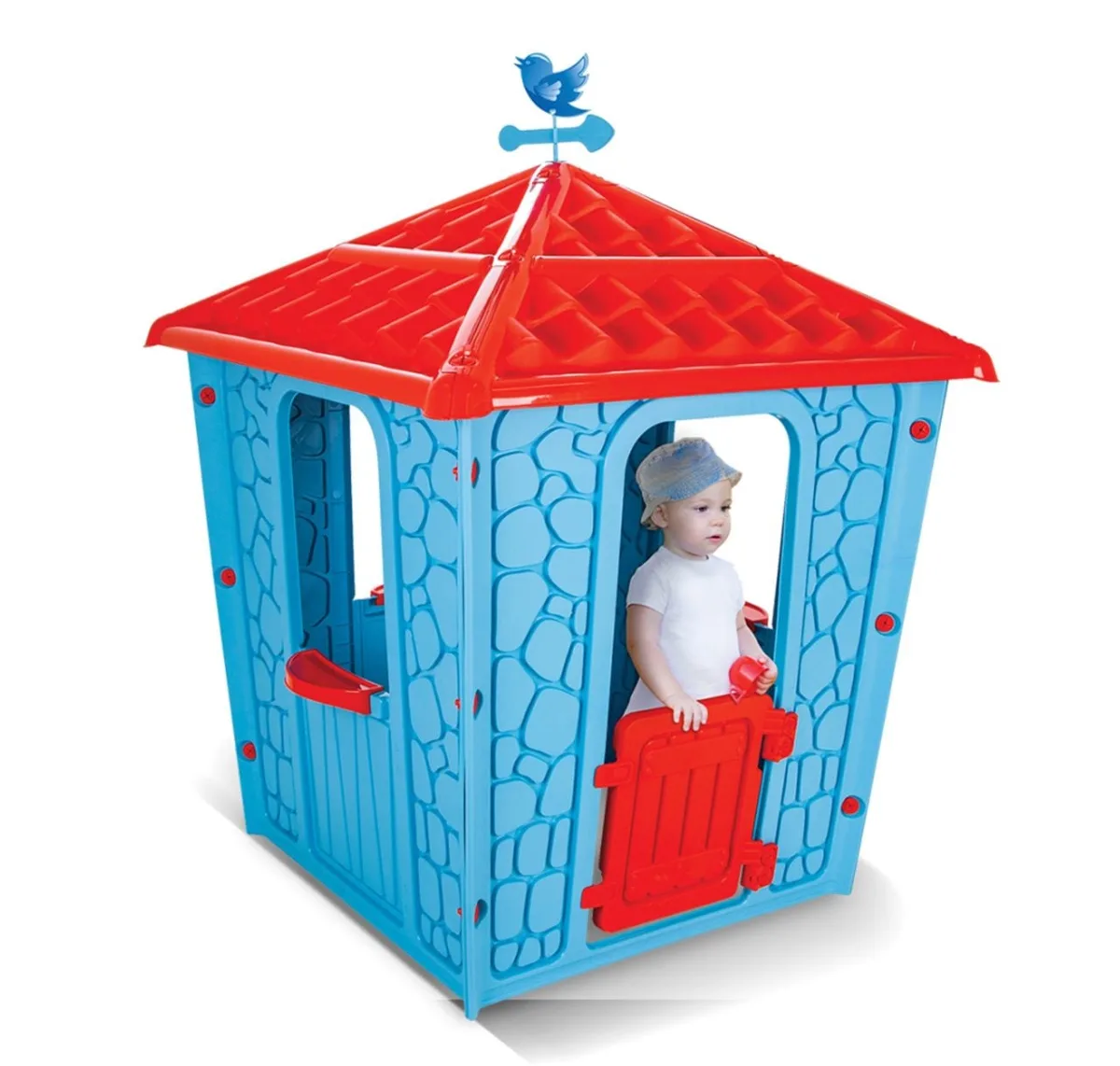 Pilsan Stone House blue plastic playhouse with red tiled roof, weather vane and red half-door, with a toddler standing inside at the entrance