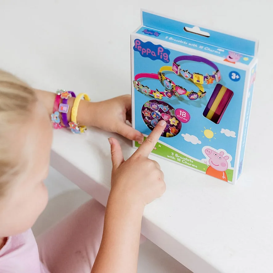 Young child wearing Peppa Pig charm bracelets with product packaging visible, showing how charms attach to colourful bands