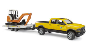 Yellow RAM 2500 pickup truck in a construction rental livery towing a white tipping trailer with an orange mini excavator.