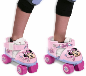 Pink Disney Minnie Mouse adjustable quad skates strapped over a child's shoes.