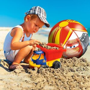 A young boy plays on the beach next to a colourful red and yellow Lightning McQueen beach ball
